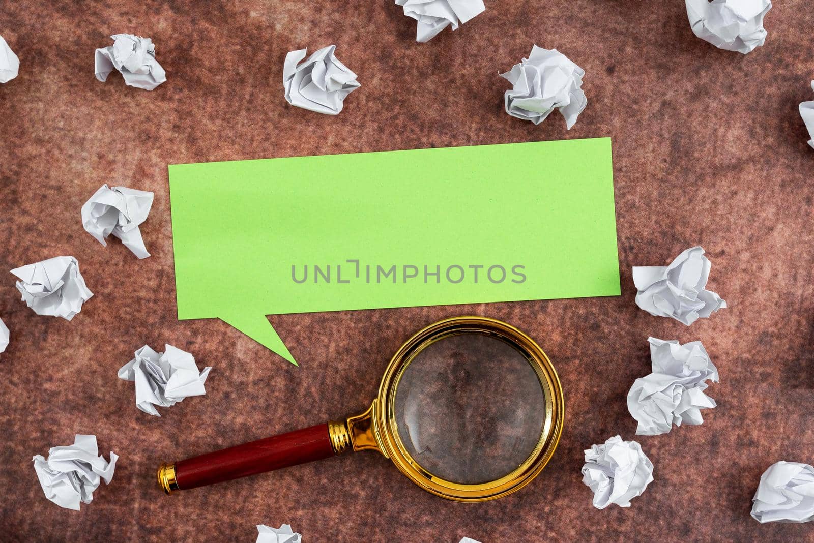 Speech Bubble Made Of Sheet With Magnifying Glass Surrounded With Crumpled Papers Over Wooden Background. It Is Showing Different Thoughts And Analyzing Strategies. by nialowwa