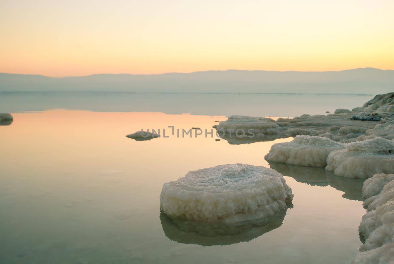 Beautiful sunrise at Dead Sea in Israel wih rocks of salt at foreground