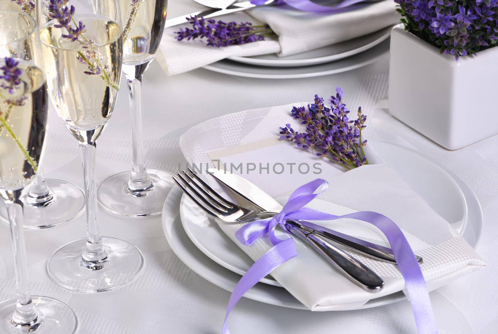 Lavender mood. Dining table in Provence style, with Lavender Champagne, folded napkin with cutlery, decorated with fresh lavender. Detail of the wedding dinner. Wedding theme ideas.