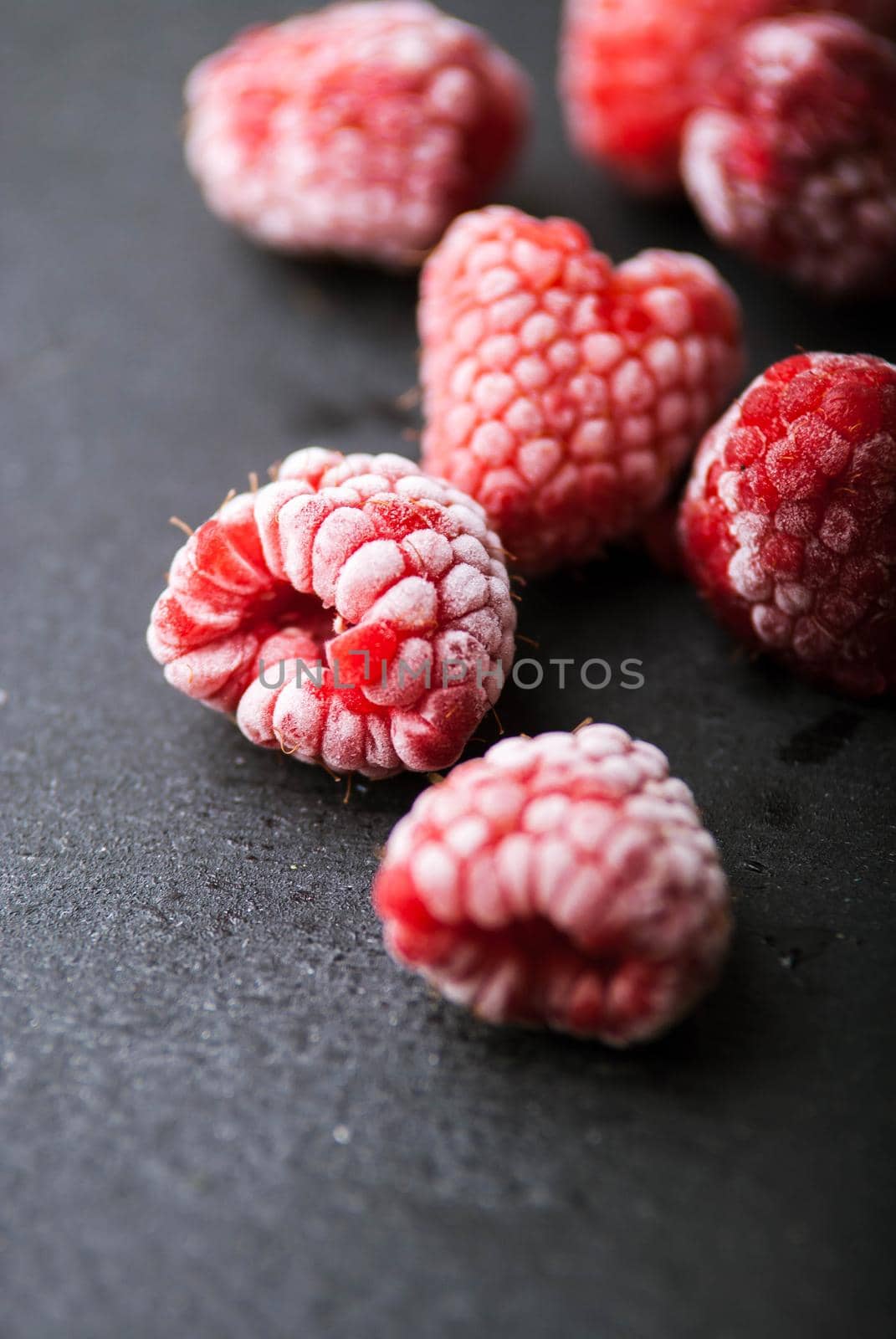 froszen raspberry on black wooden background by maramorosz