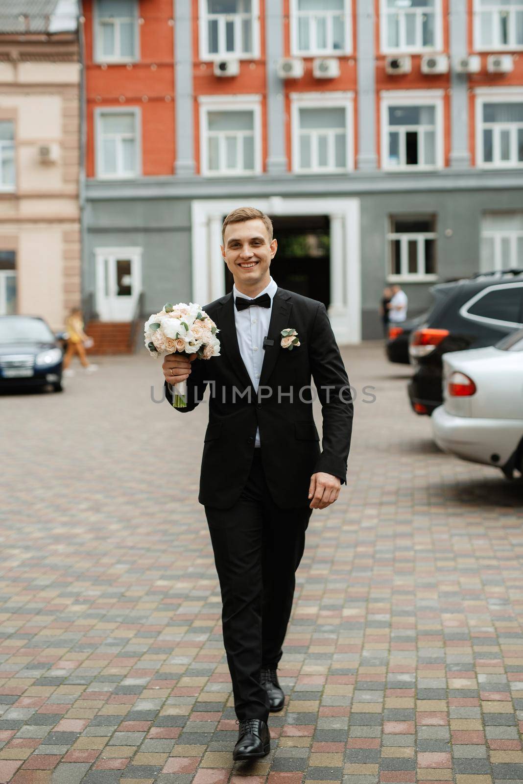 portrait of a young guy groom in a black suit on a rainy day