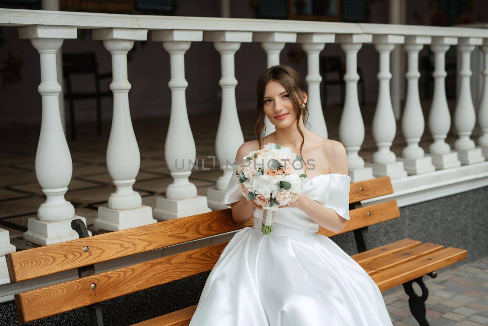 portrait of a young bride girl in a short white dress on a rainy day