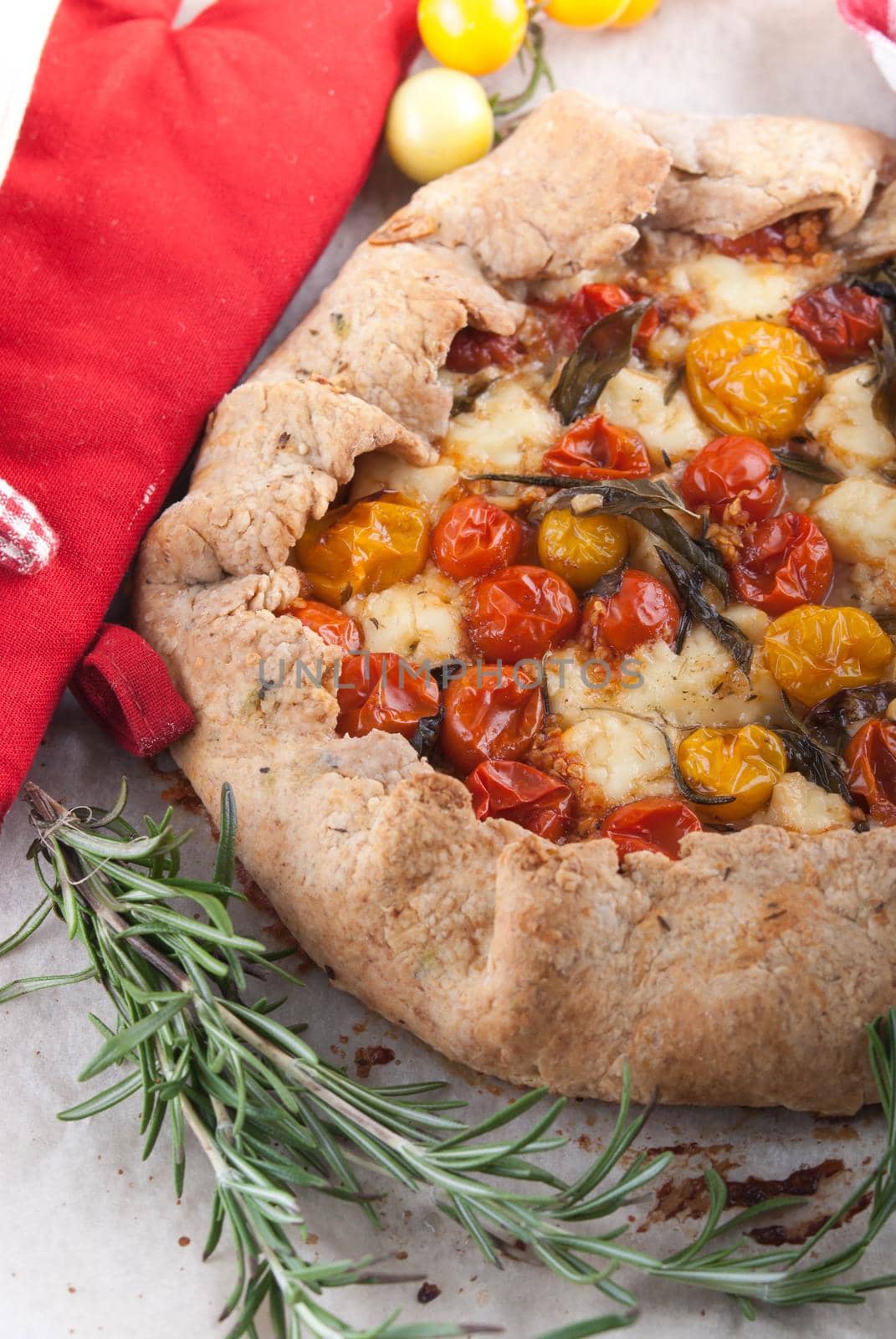 delicious homemade galetta pie with cherry tomatoes, feta cheese and basil and rosmarim herbs