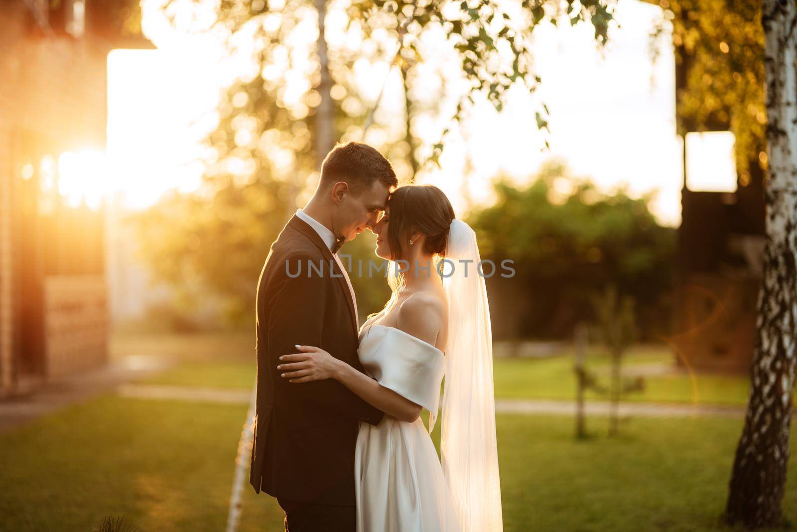 young couple the groom in a black suit and the bride in a white short dress on a walk in the village