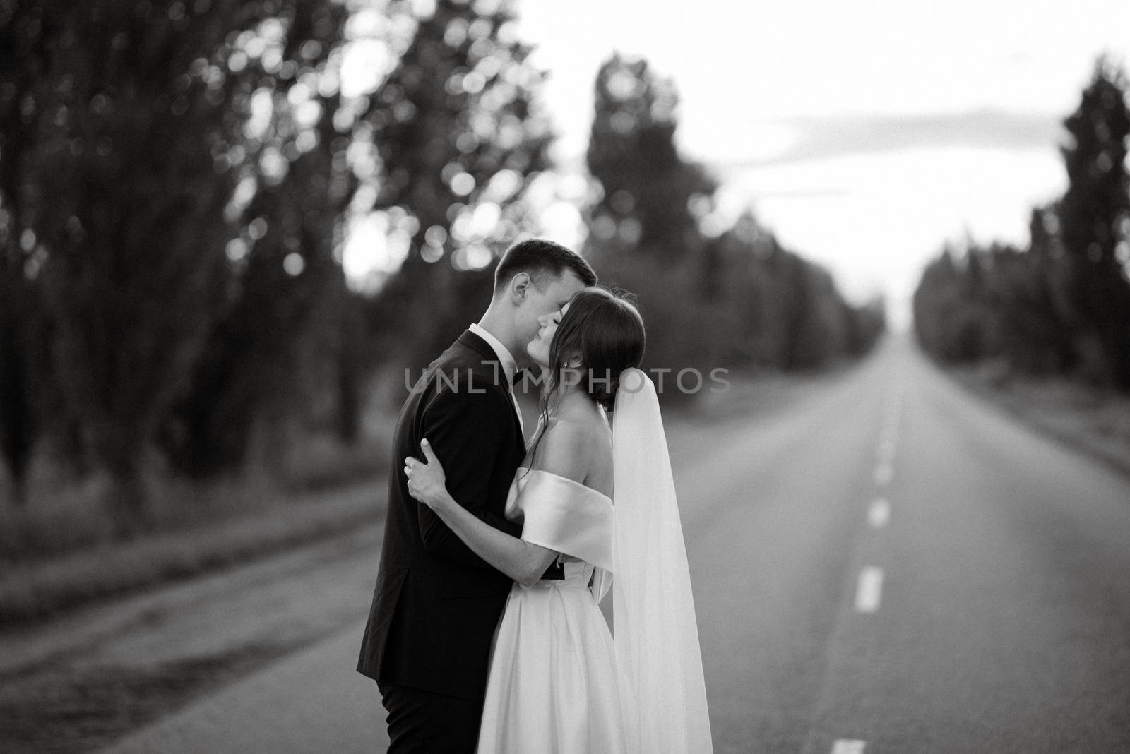 young couple bride and groom in a white short dress walking in the rain