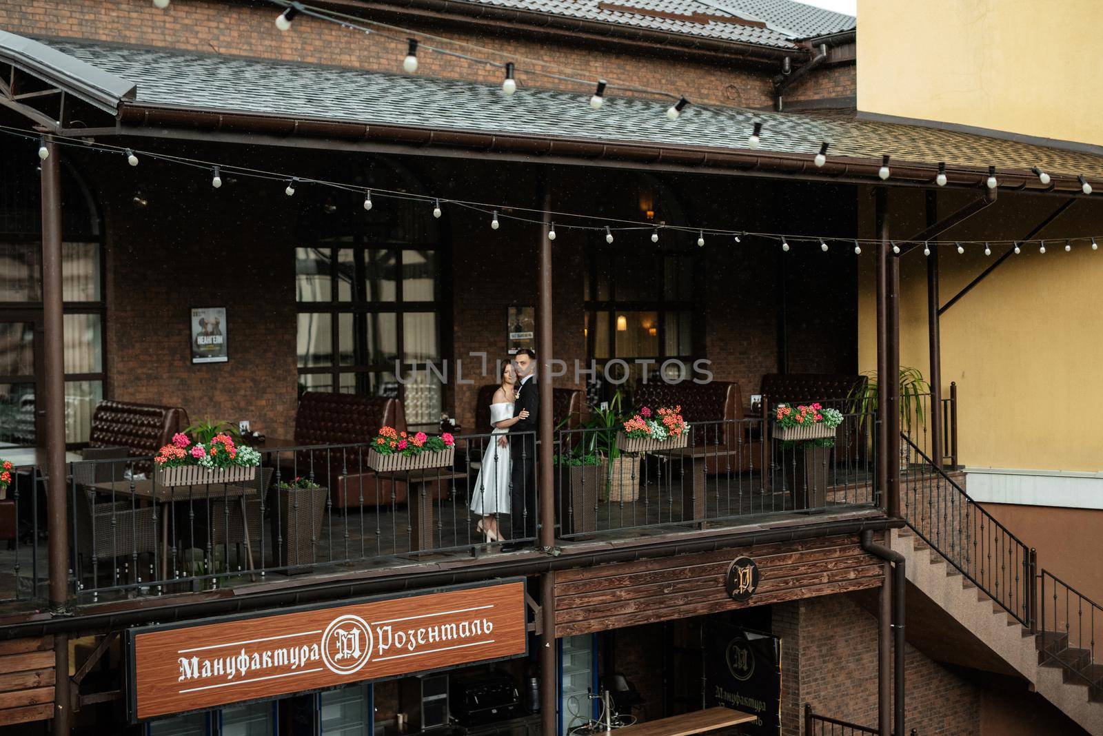 young couple bride and groom in a white short dress walking in the rain