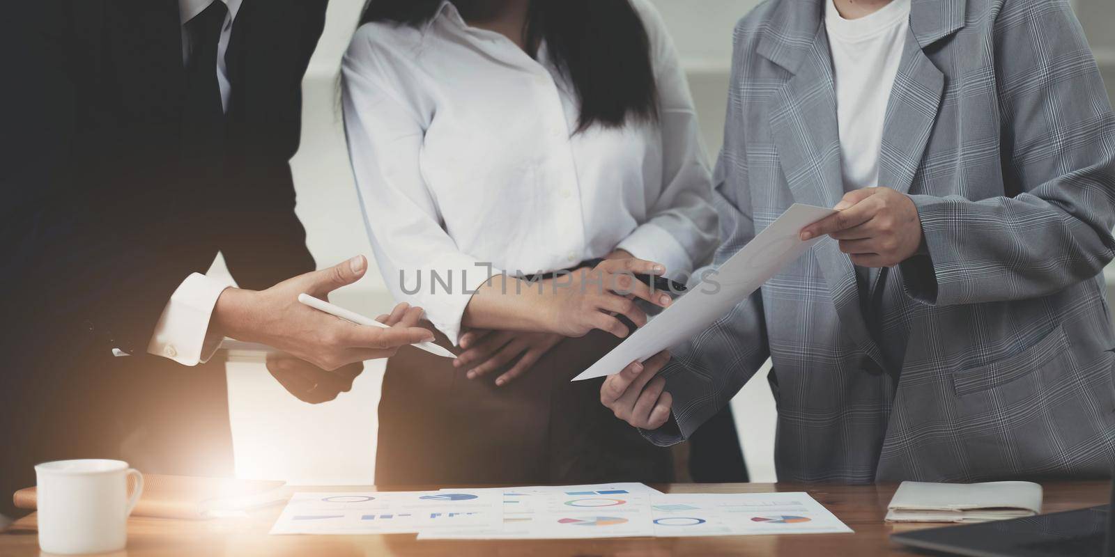 Close up of diverse businesspeople cooperate work together discussing company financial statistics, multiracial colleagues employees collaborate brainstorm with finance document at meeting by wichayada