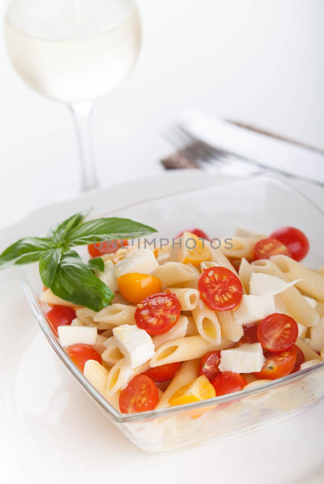 bright and tasty pasta salad with fresh mozarella and cherry tomatoes, basil