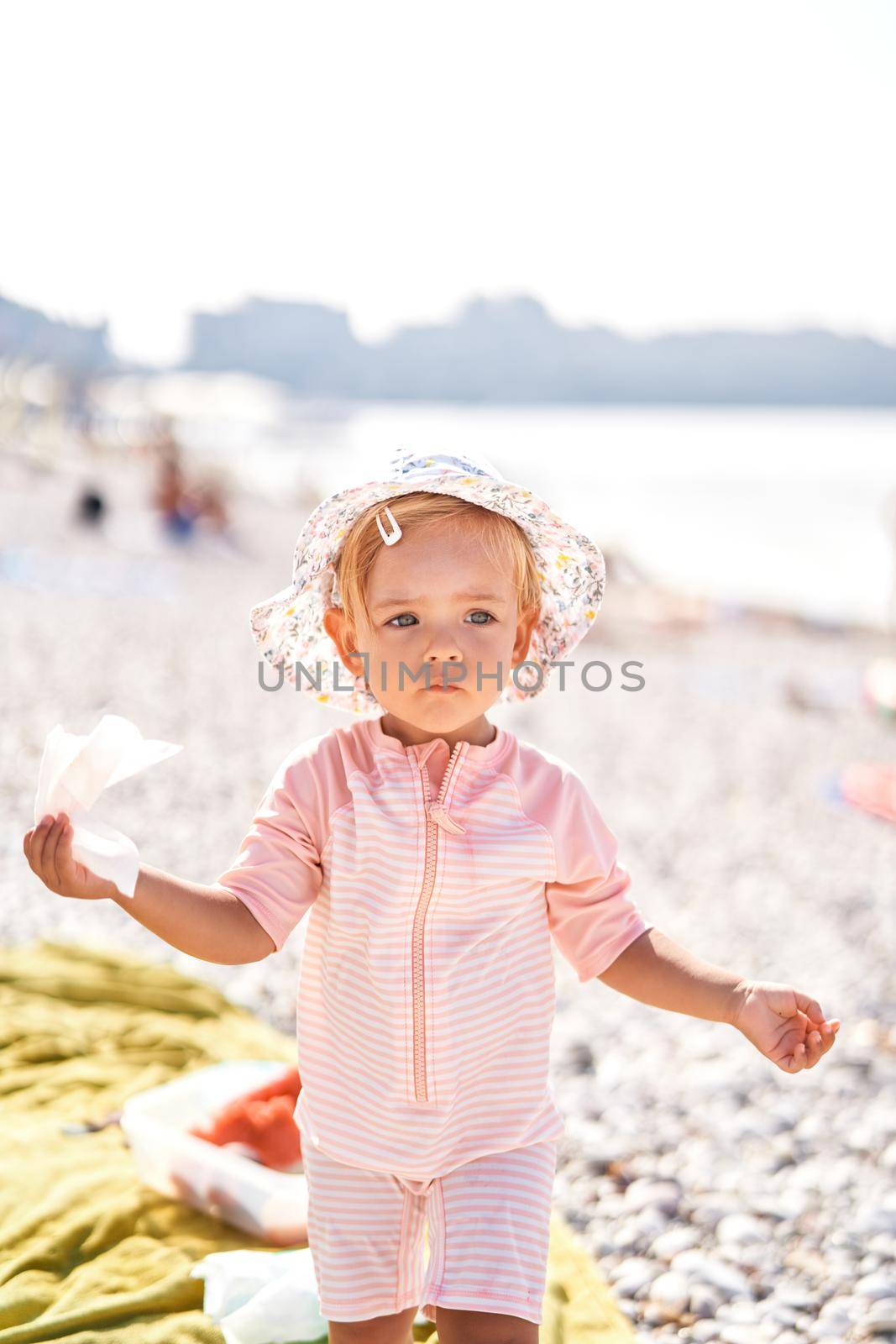 Little girl in a panama hat with a napkin in her hand on the beach. High quality photo