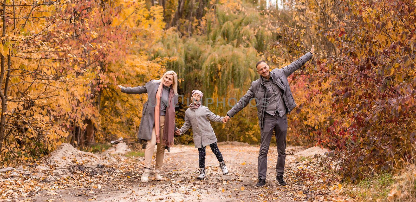 Young happy family while walking in the autumn park