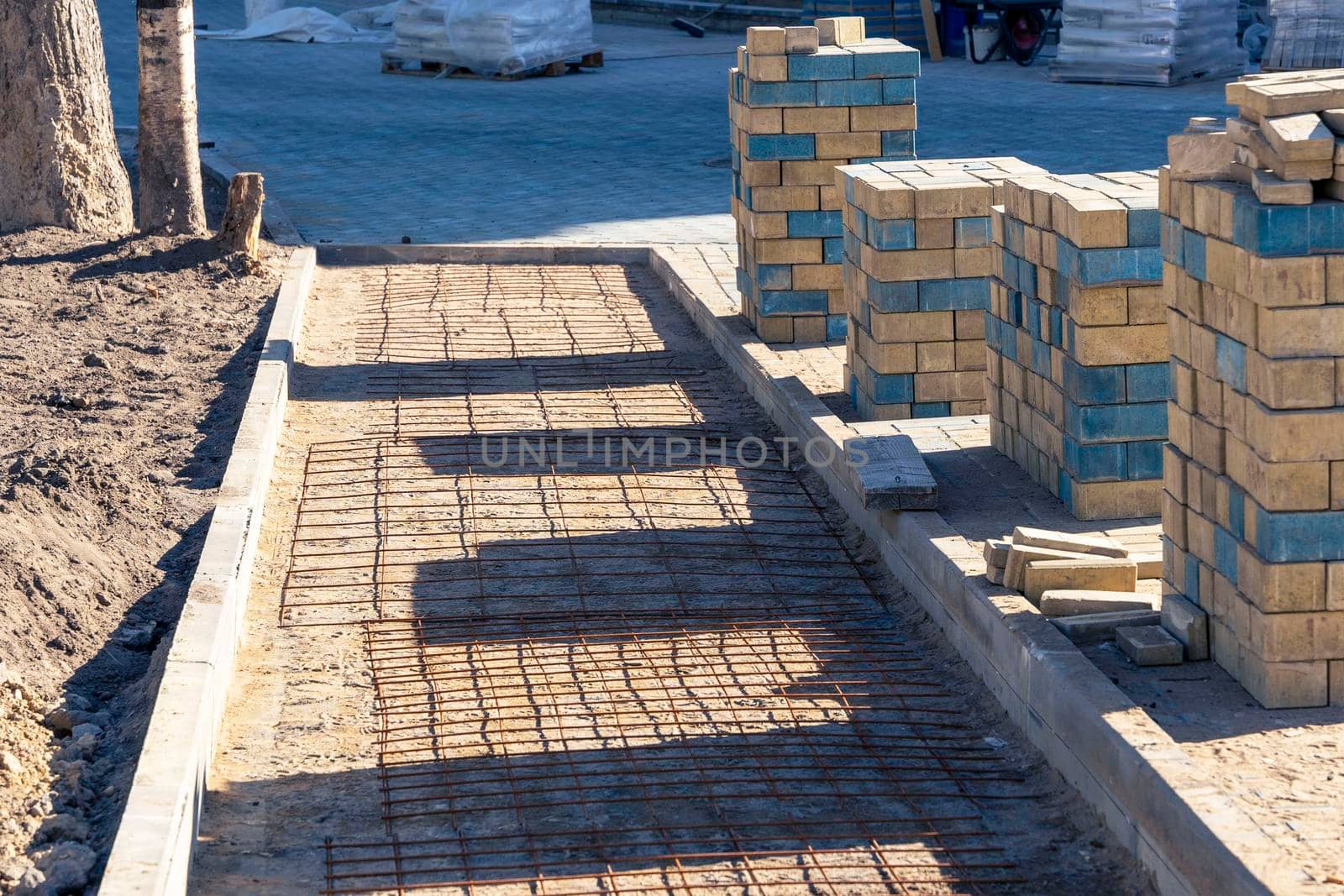 a new pedestrian walkway under construction and prepared stacks of new colored paving slabs for paving the complex length of the path in the city park. improvement of the city, paving of sites