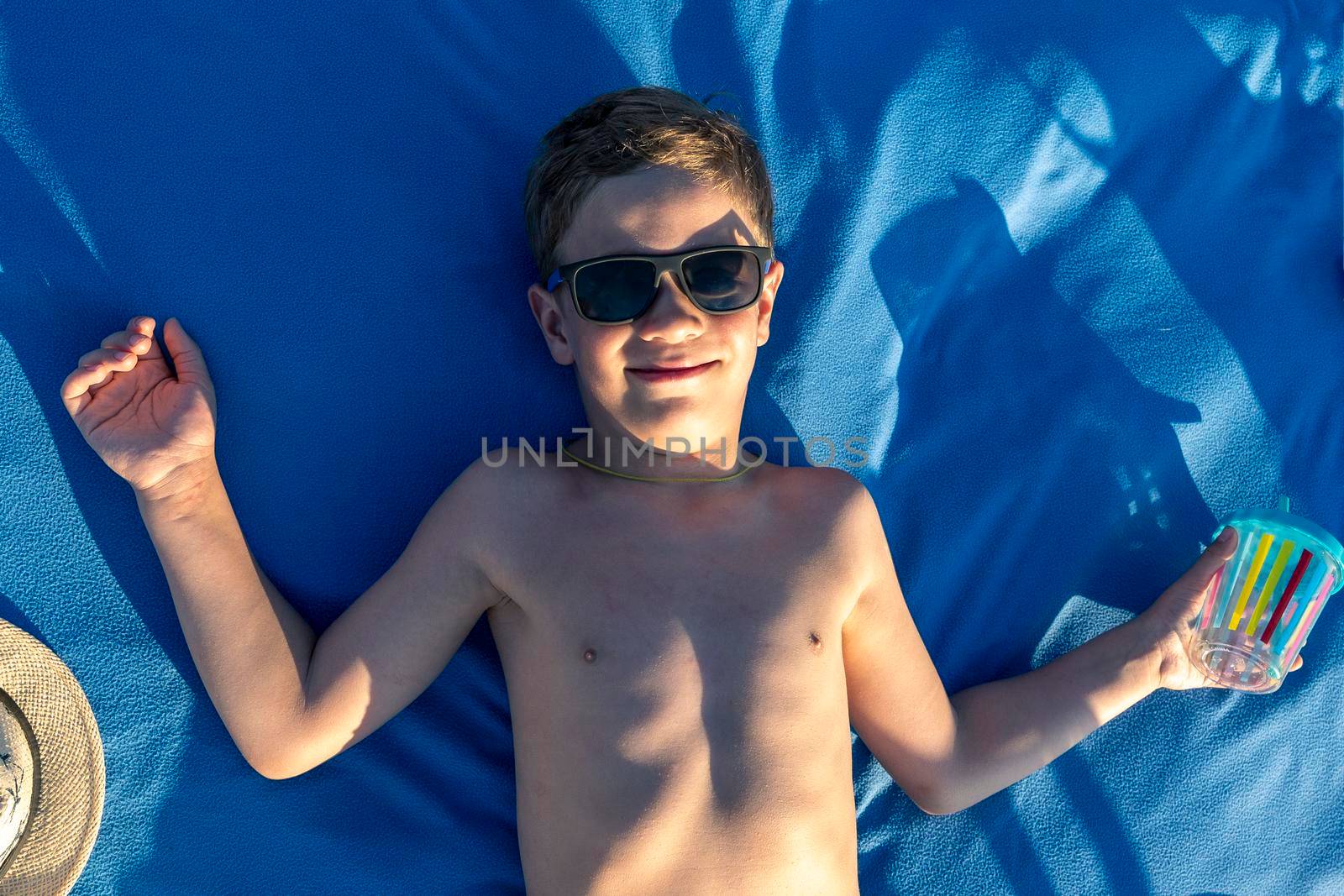 happy boy in sunglasses with bare torso sunbathing lying on the beach by audiznam2609