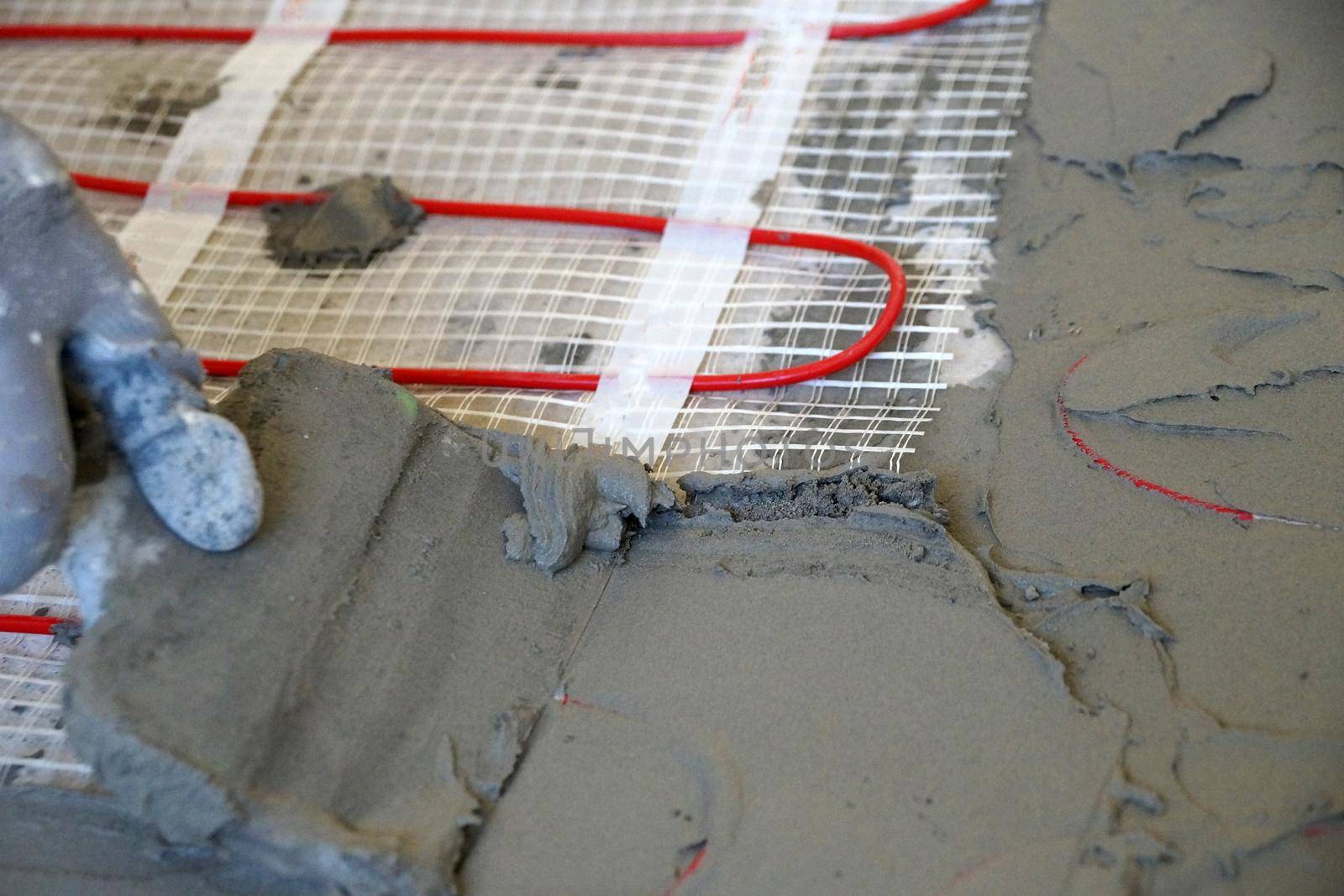 laying an electric underfloor heating under a cement screed close-up