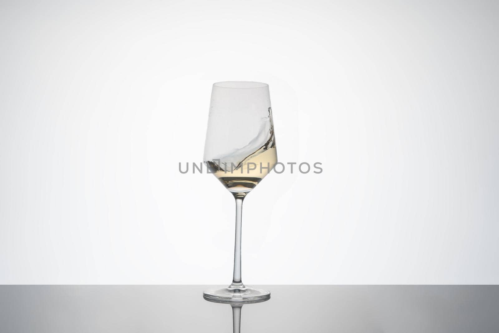 white wine movement inside a crystal glass. white wine glass on white background with reflection on the base. image for cutout. by CatPhotography