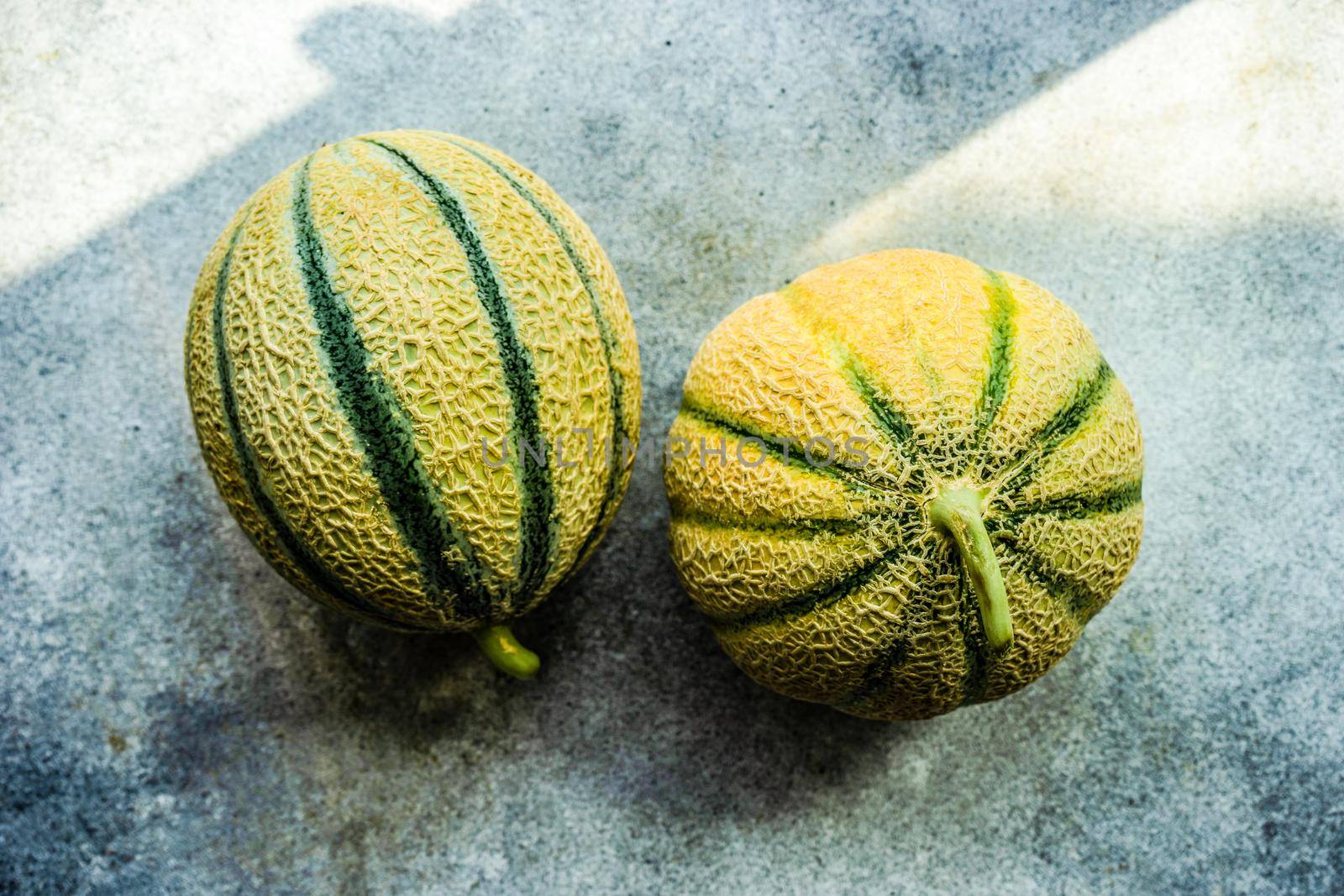 Textured fresh and ripe cantaloupe melons on concrete background