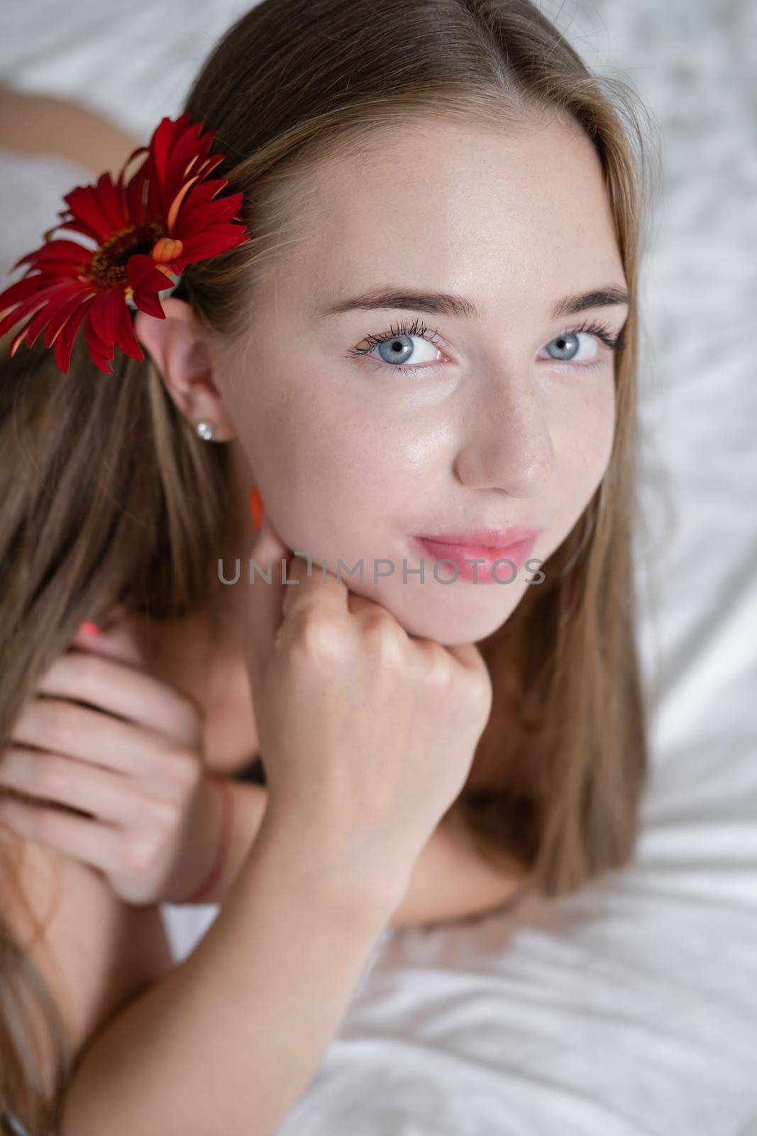 Calm woman with flower lying on her bed. morning routine. successful date. bright white bedroom.