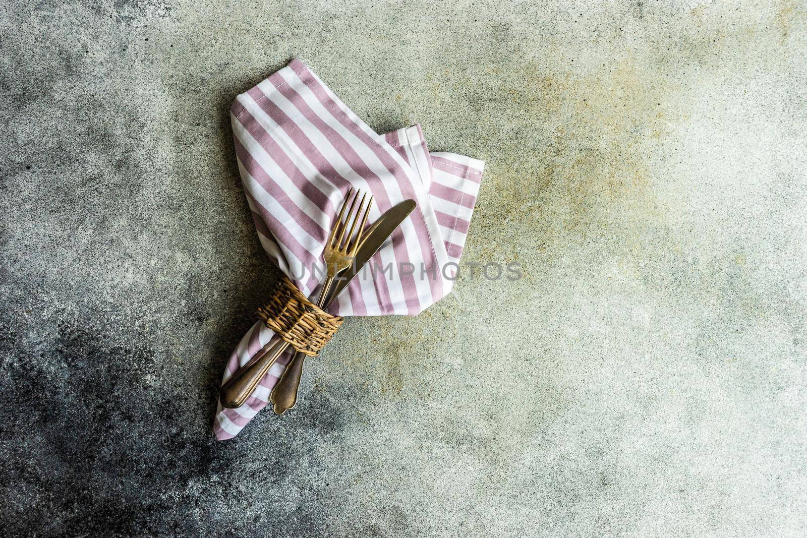 Cutlery set with textile napkin and silverware on concrete table