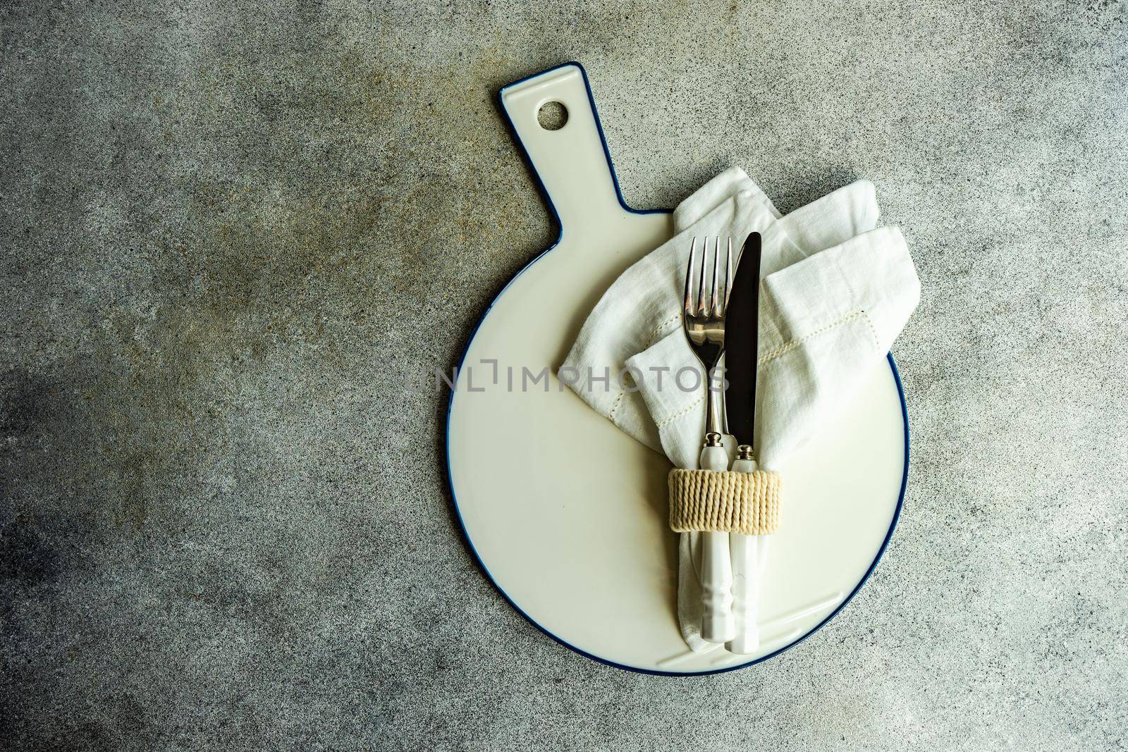 Cutlery set with textile napkin and silverware on concrete table