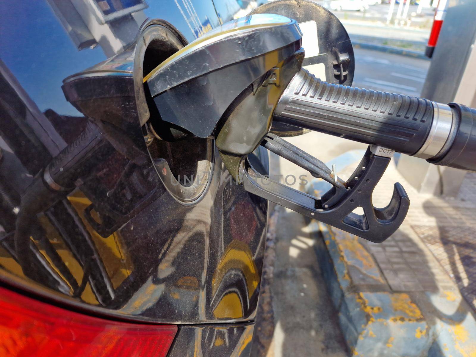 Hand refilling the car with fuel, close-up. by barcielaphoto