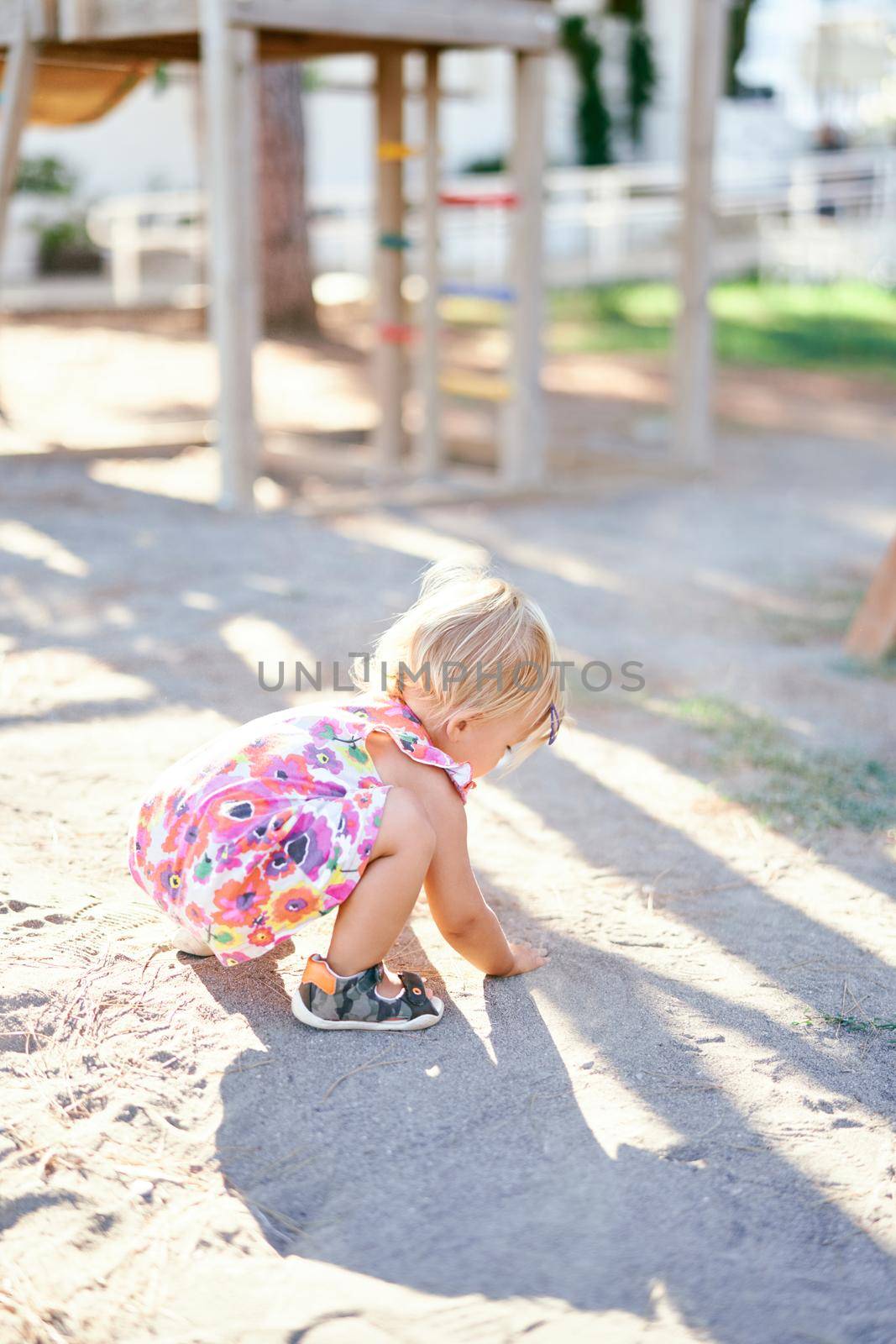 Little girl crouched down and draws with her hands on the ground. High quality photo