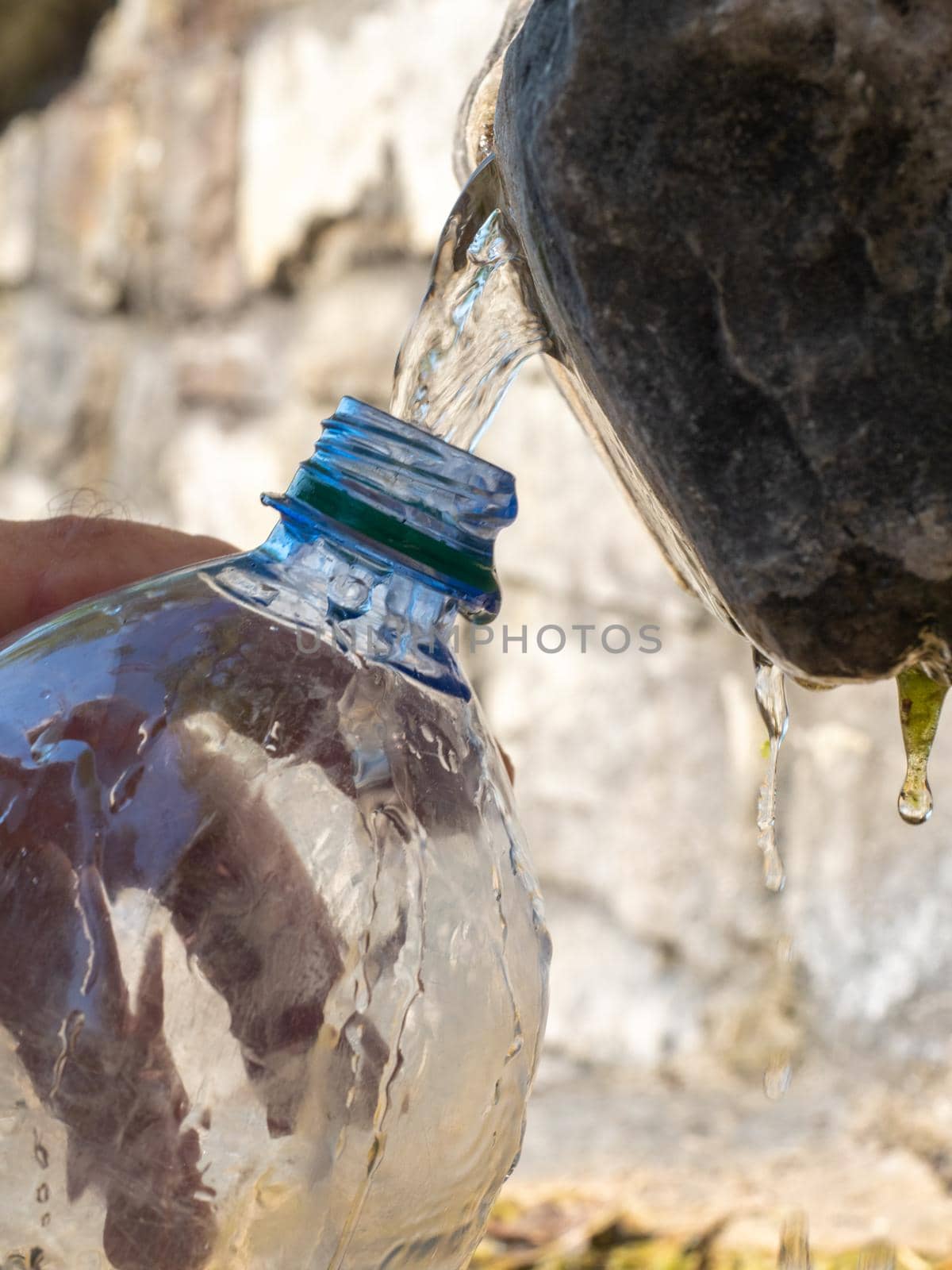 filling a plastic bottle with fresh spring water in a public source by verbano