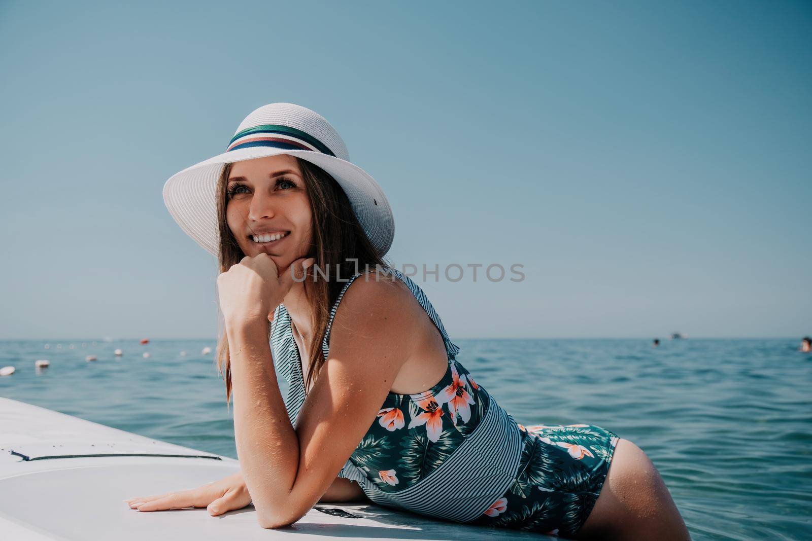 Happy young woman in swimsuits doing yoga on sup board in calm sea, early morning. Balanced pose - concept of healthy life and natural balance between body and mental development