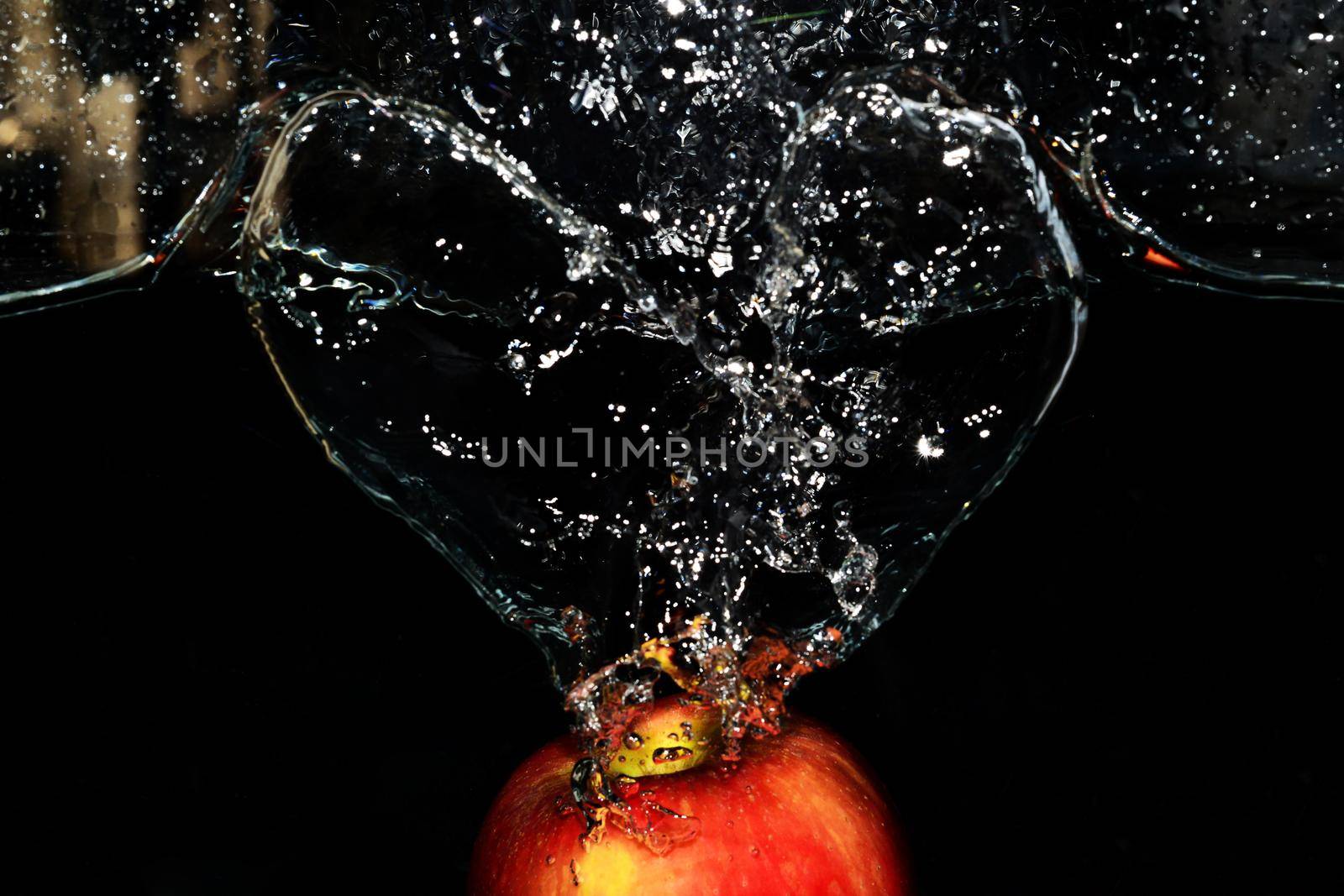 Red apple splashes in the water on black background