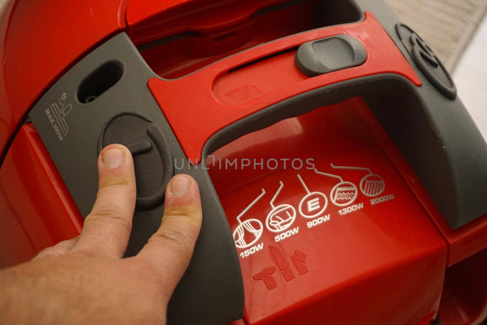 Man pushing power button on vacuum cleaner close up view