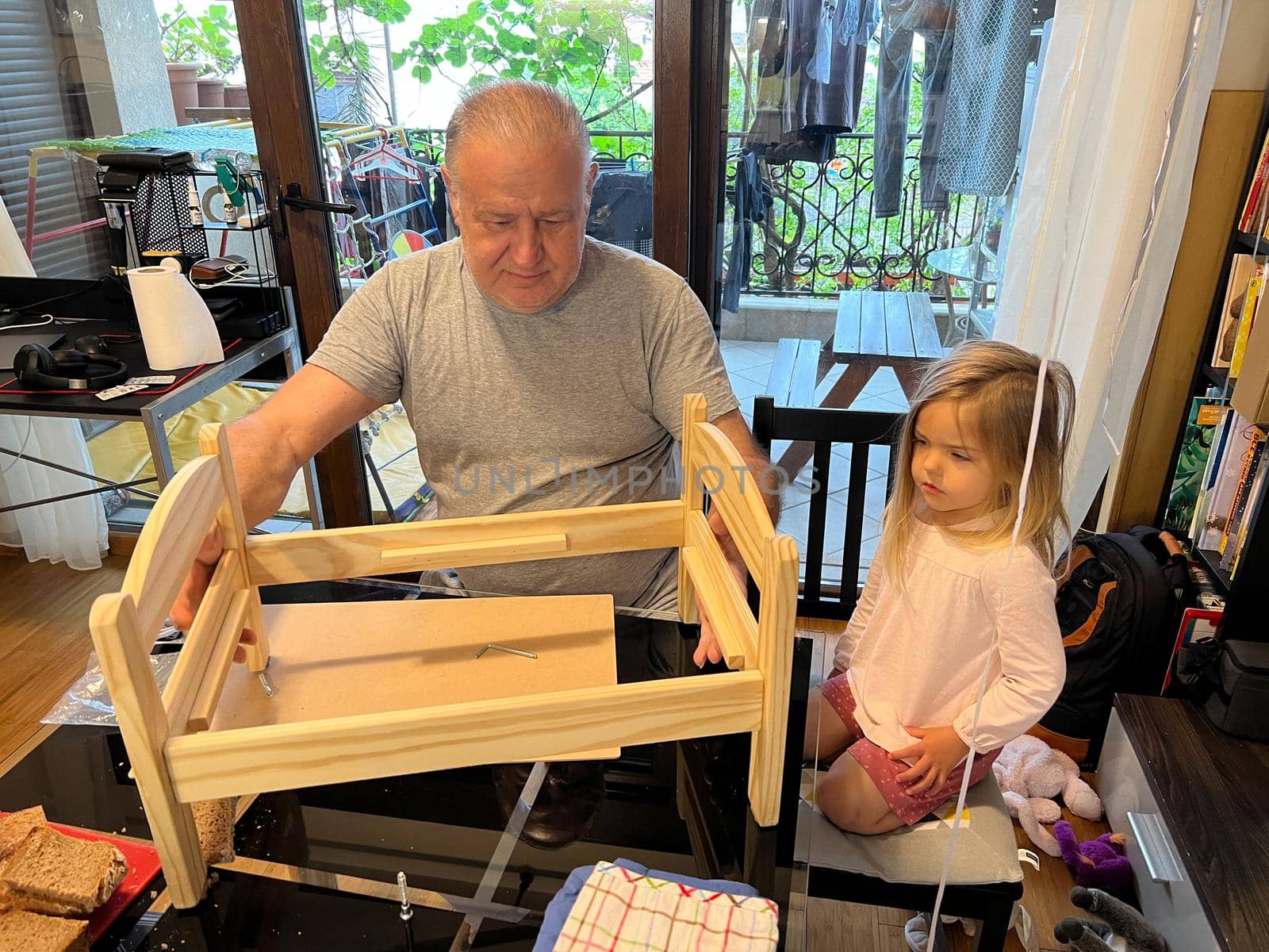 Grandpa assembled a toy wooden bed for a little girl. High quality photo
