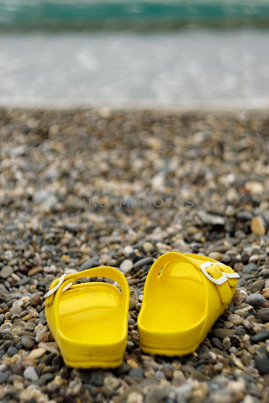 Yellow woman slippers on pebble stone beach close up view
