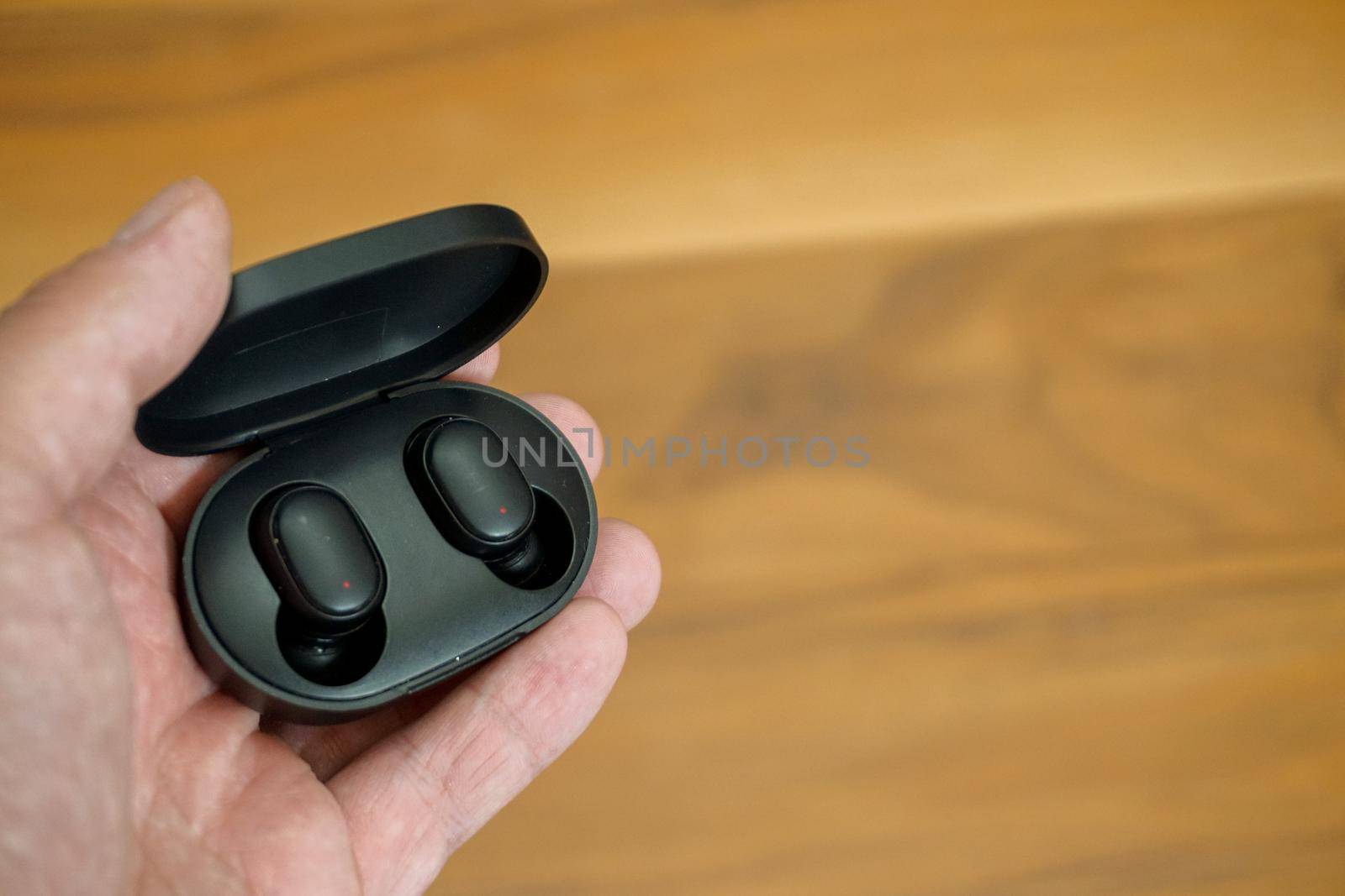 Wireless earphones with charge case in man hand close up view by tasci