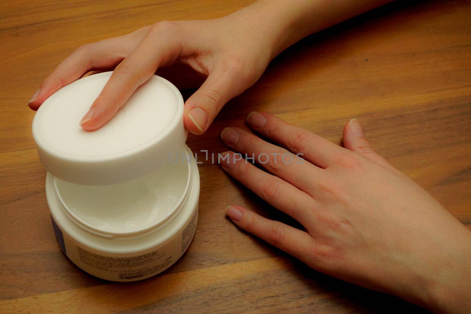 Woman applies hand cream to her hand on wooden isolated background by tasci