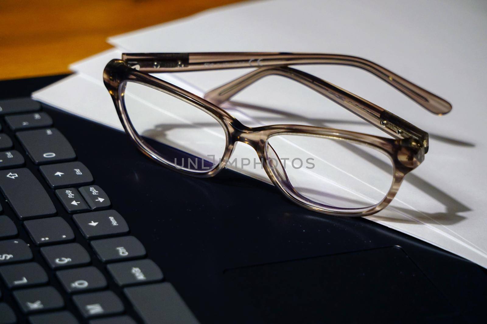 Glasses laptop keyboard and notes on wooden background business concept close up view