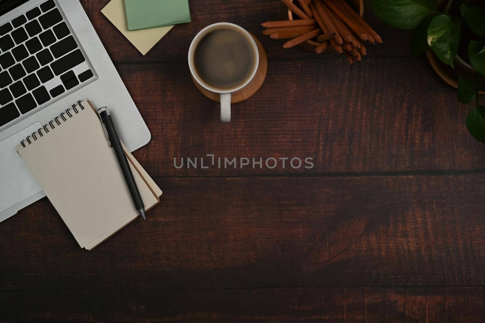 Top view laptop computer, notepad, sticky notes and coffee cup on wooden background with copy space.