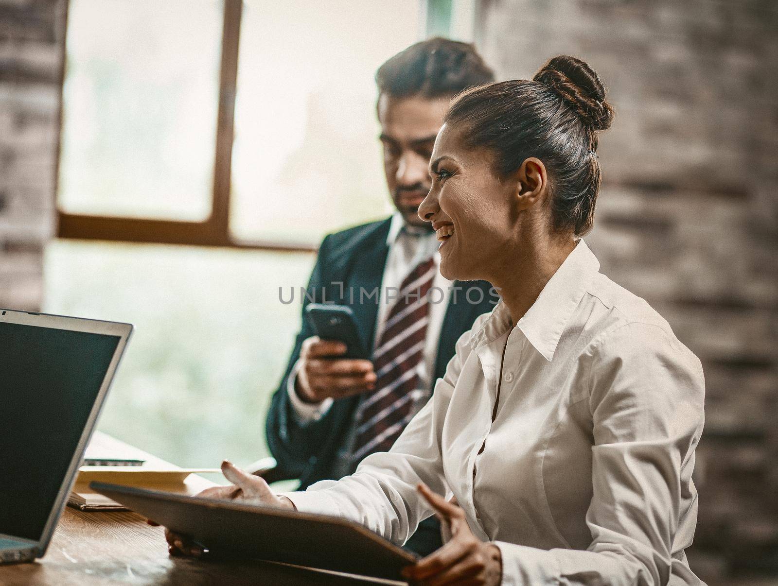 Smilling Businesswoman Holding Digital Tablet, Side View Of Charming Female Office Worker Toothy Smiling During Conversation With Her Coworkers At Business Meeting, Dutch Angle Shot, Toned Image