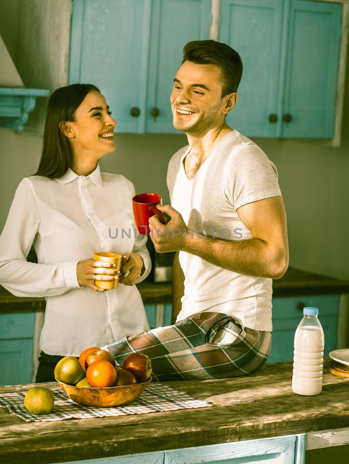 Happy Couple Toothy Smiles At Kitchen Interior by LipikStockMedia