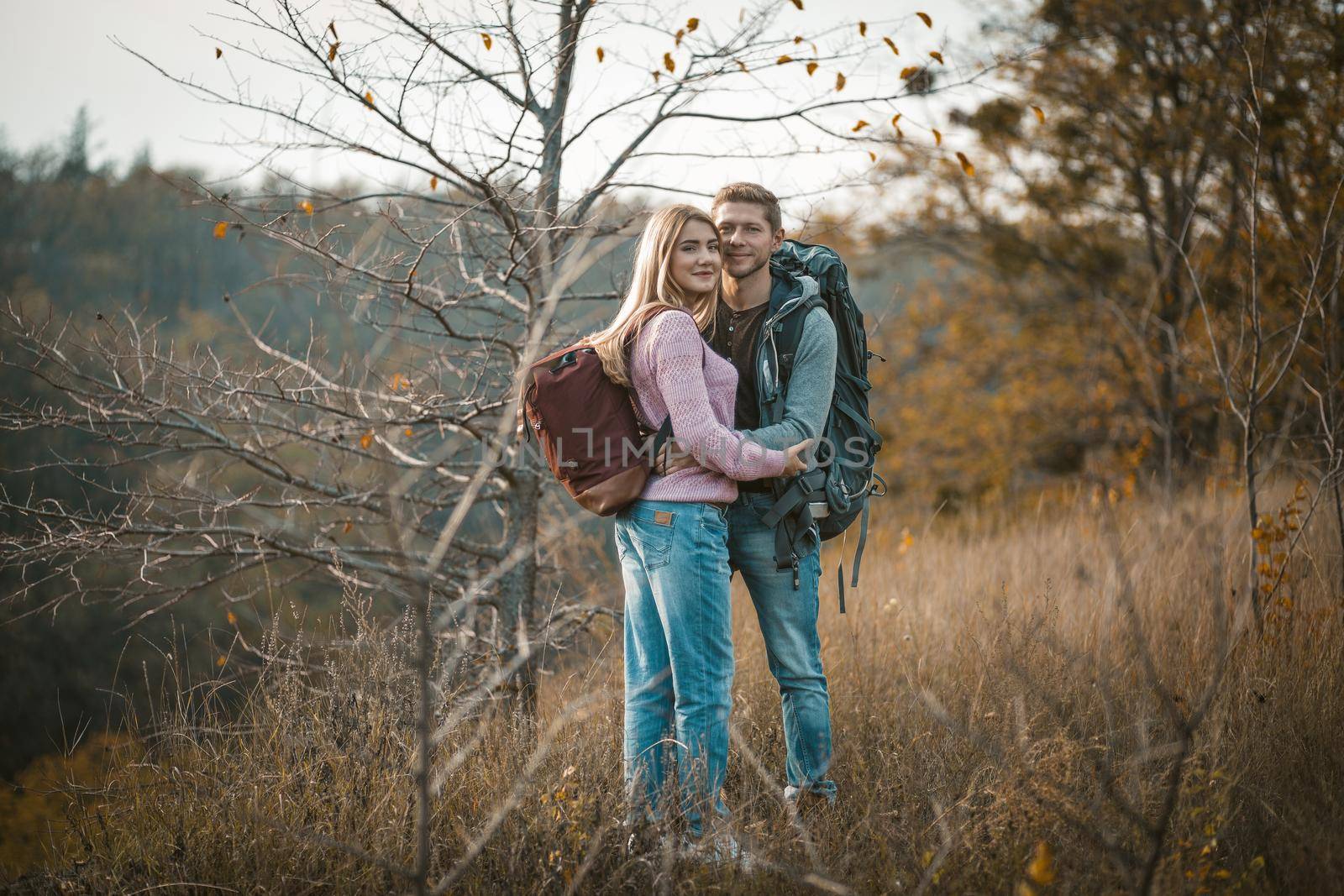 Smiling Couple With Backpacks Standing Embraced by LipikStockMedia