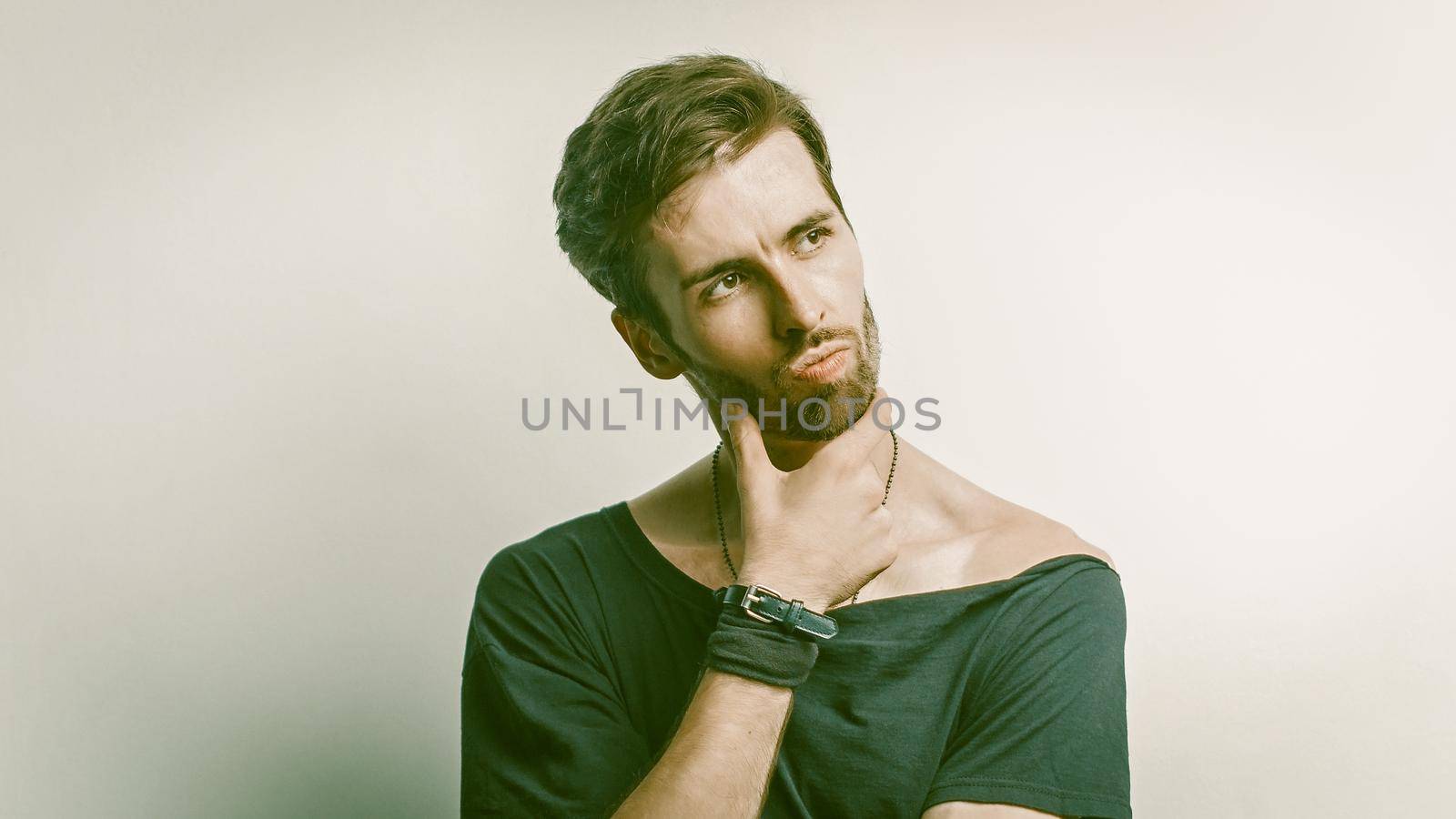 Handsome Bearded Man Is Looking Thoughtfully To The Right, Half-Length Portrait Of Hipster Touching His Beard With Hand And Pensively Posing, Copy Space On The Right