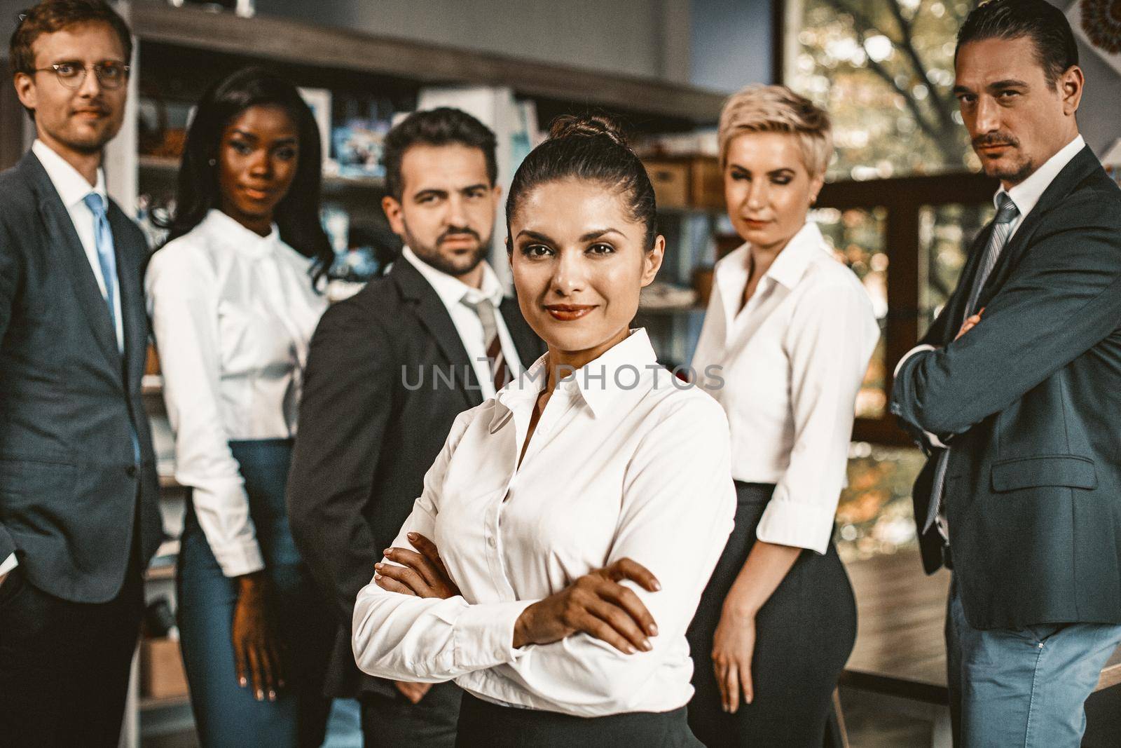 Portrait Of Multiethnic Business Group, Well-Dressed People Stand Posing In Office, Focus On Smiling Woman Standing In Foreground With Crossed Arms, Friendly Diverse Team On Background, Toned Image