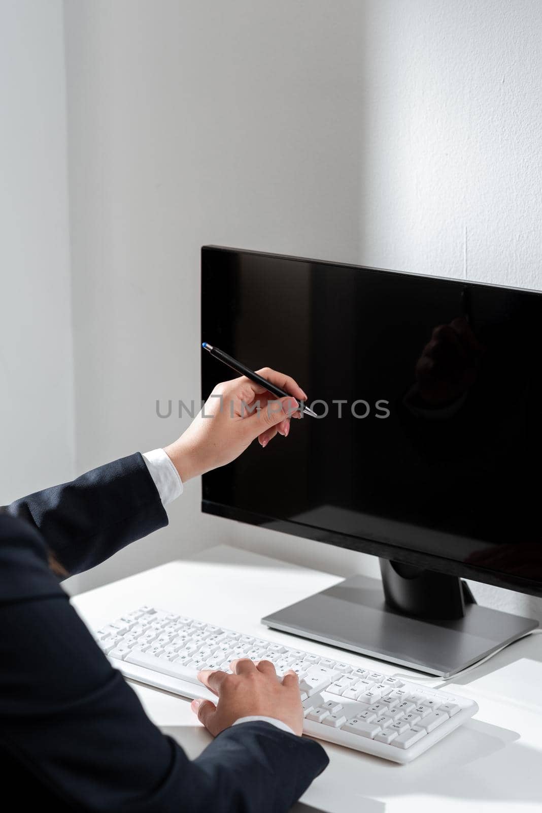 Businesswoman Typing Recent Updates On Lap Top Keyboard On Desk And Pointing Important Ideas With Pen. Woman In Office Writing Late Messages On Computer. by nialowwa