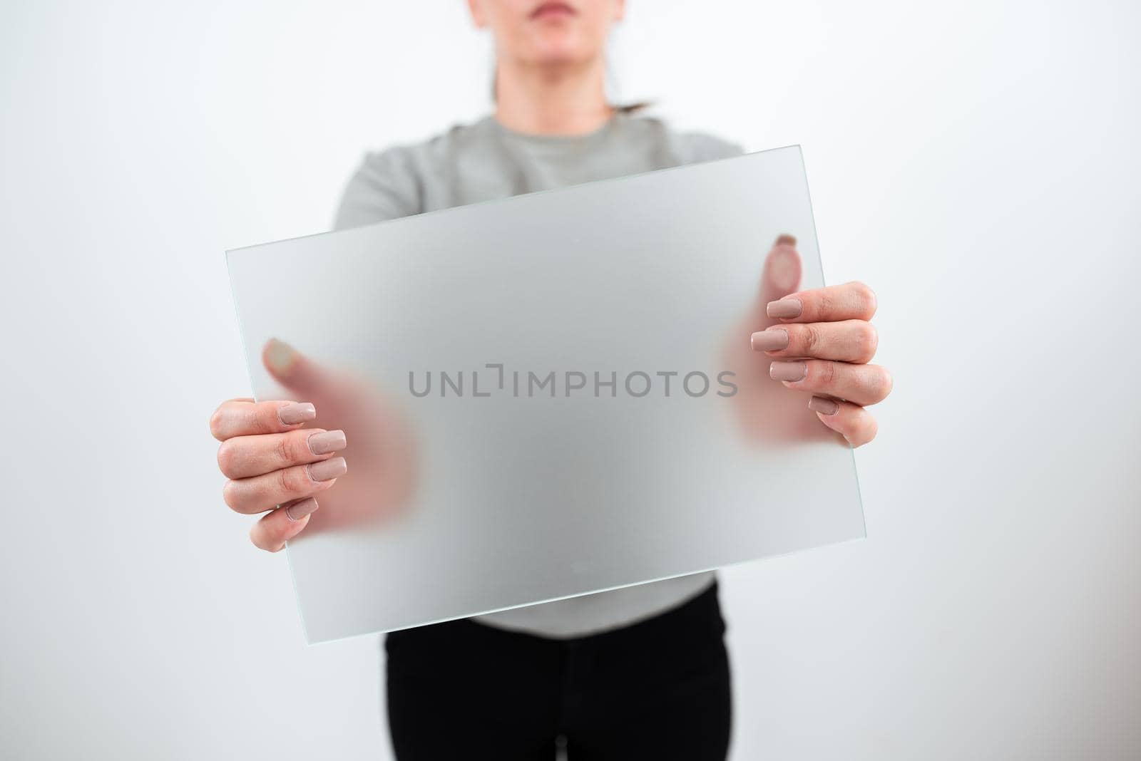 Businesswoman Holding Blank Placard And Presenting Important Sales Data. Female Worker Wearing Smart Casual And With Banner In Hands Advertising The Business. by nialowwa