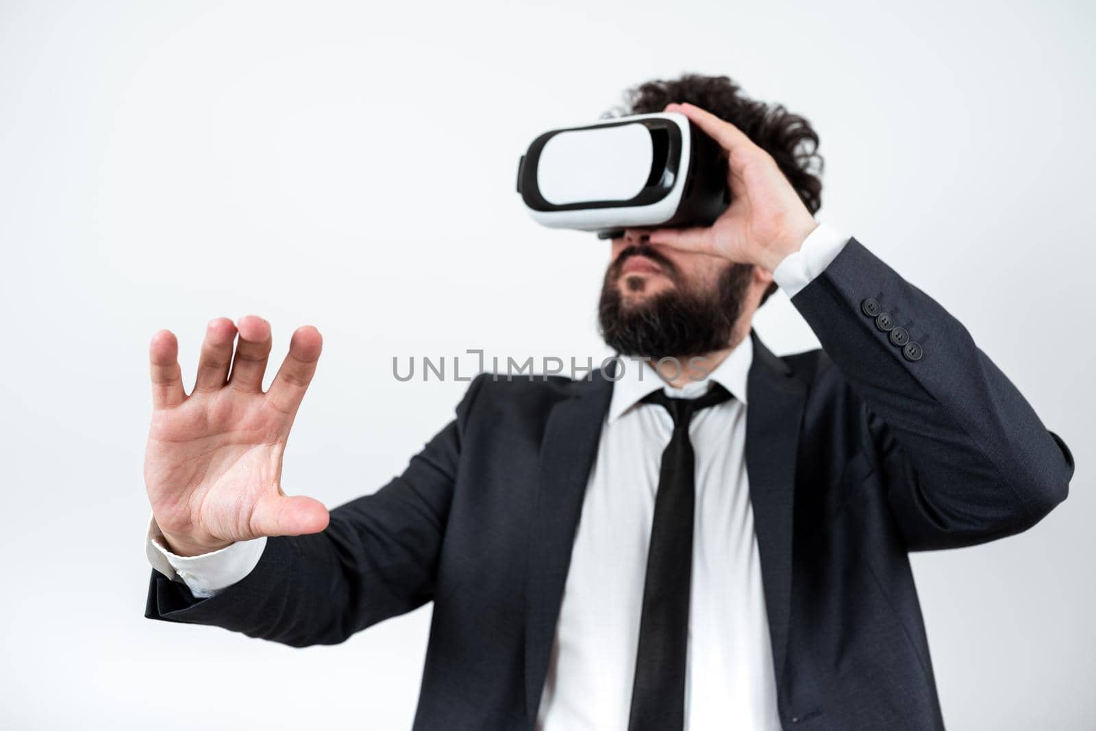 Man Wearing Vr Glasses And Presenting Important Messages With One Hand. Businessman Having Virtual Reality Eyeglasses And Showing Crutial Informations. by nialowwa