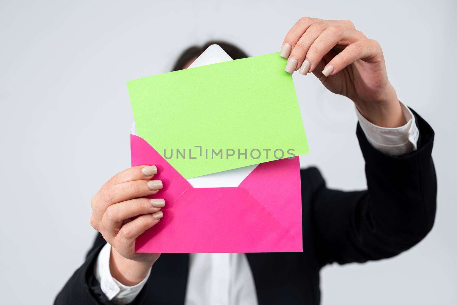 Hands Of Businesswoman Putting Important Letter In Envelope For Sending Through Mail. Woman Wearing Suit Holding Postcard With Crucial Business Information And Message. by nialowwa