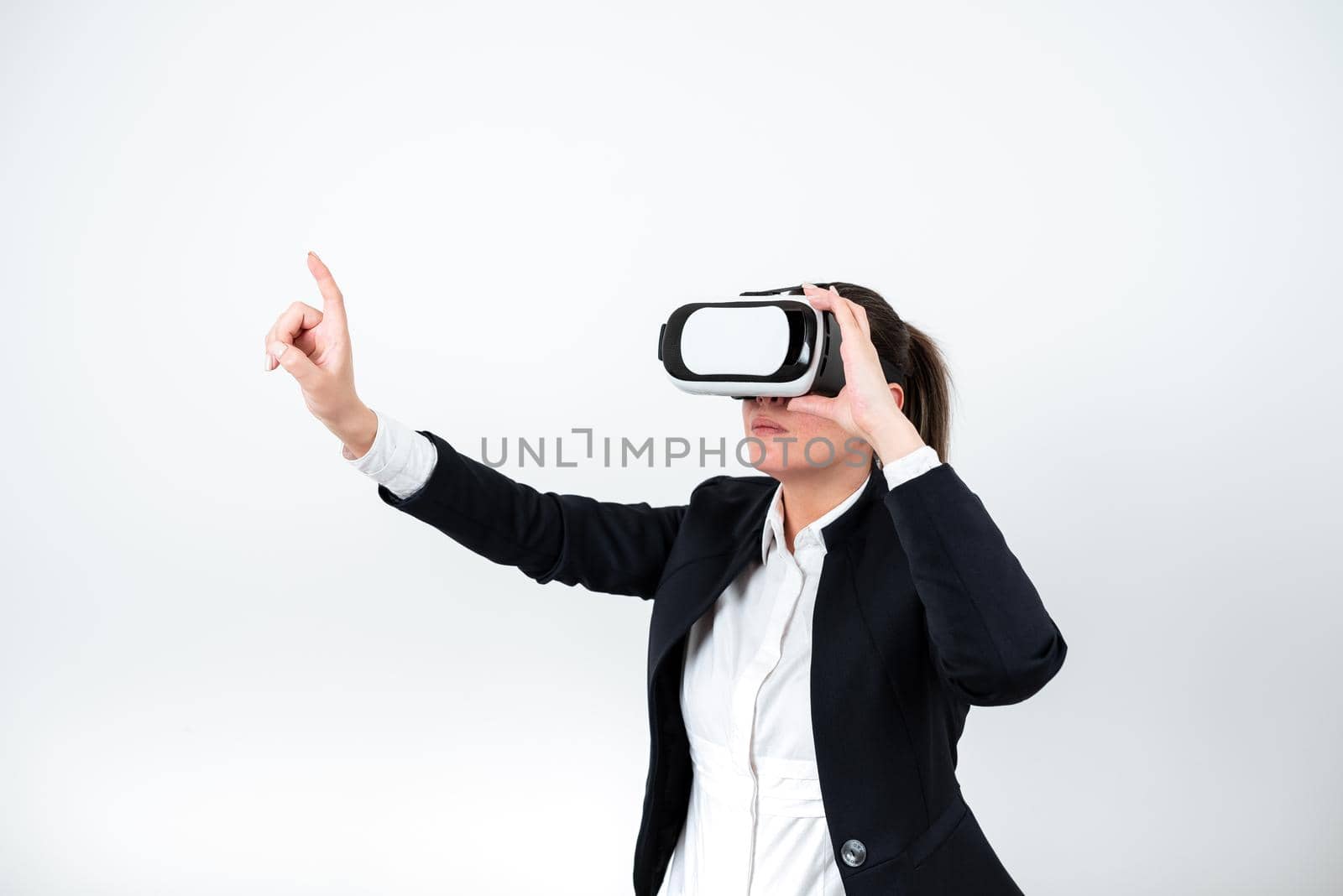 Woman Wearing Vr Glasses And Pointing On Important Messages With One Finger. Businesswoman Having Virtual Reality Eyeglasses And Showing Crutial Informations. by nialowwa