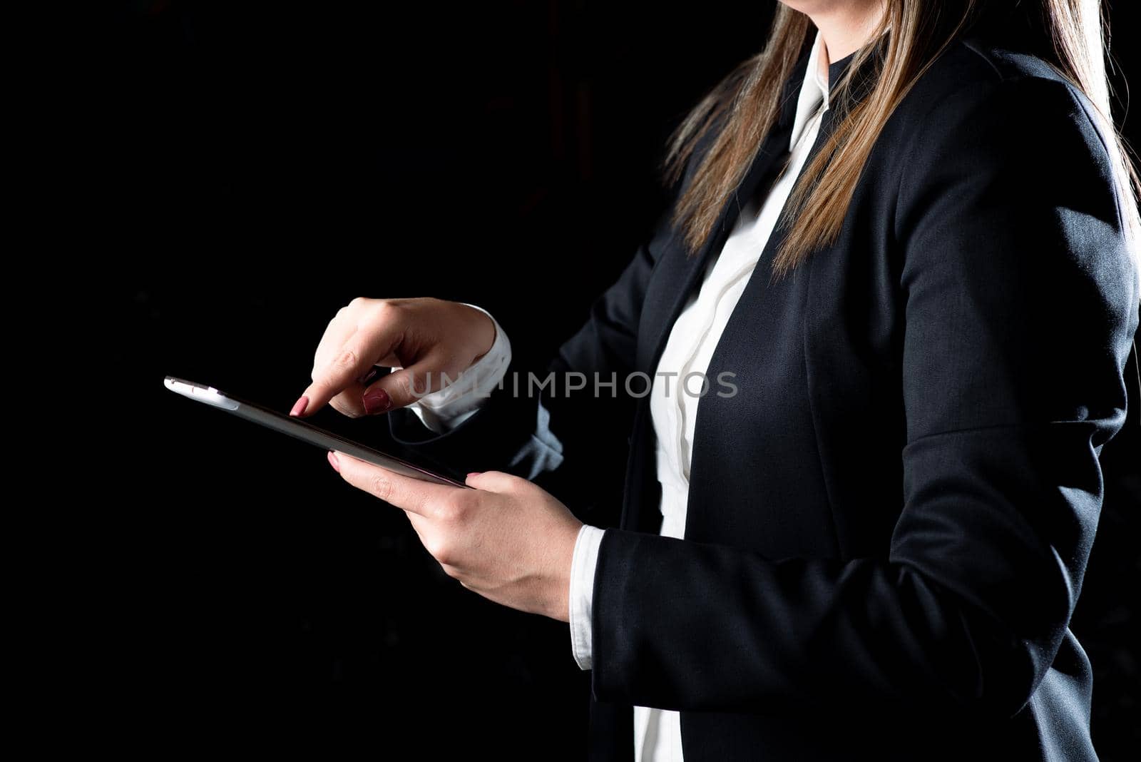 Businesswoman Holding Tablet And Pressing On It. Woman Having Phone In Hand And Pointing On It. Executive Presenting Important Informations On Cellphone. by nialowwa