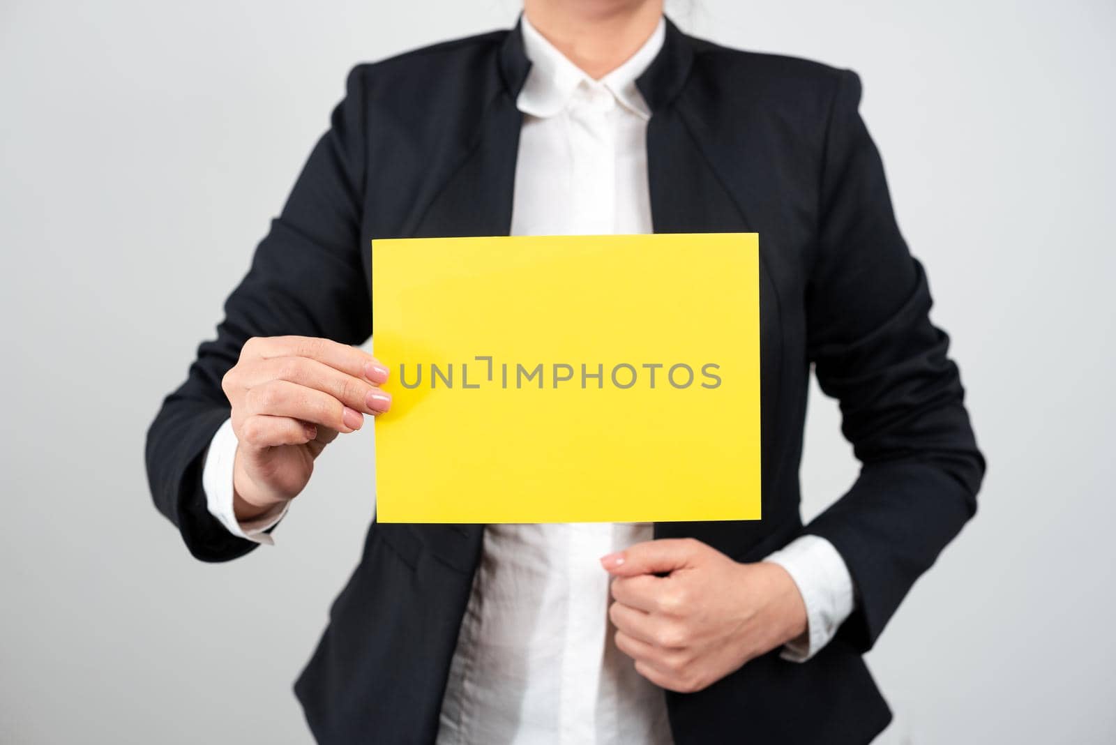 Businesswoman Holding Note With Important Message With One Hand. Woman Presenting Crutial Information On Piece Of Paper. Executive Showing Critical Announcement. by nialowwa