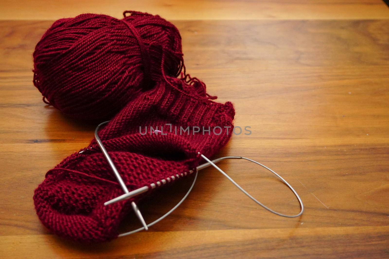 Wool knitting on wooden table close up by tasci