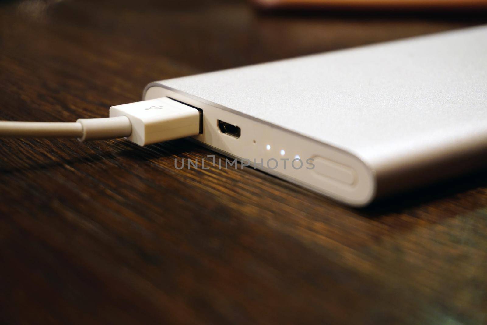 Powerbank charging smartphone on wooden background close up view