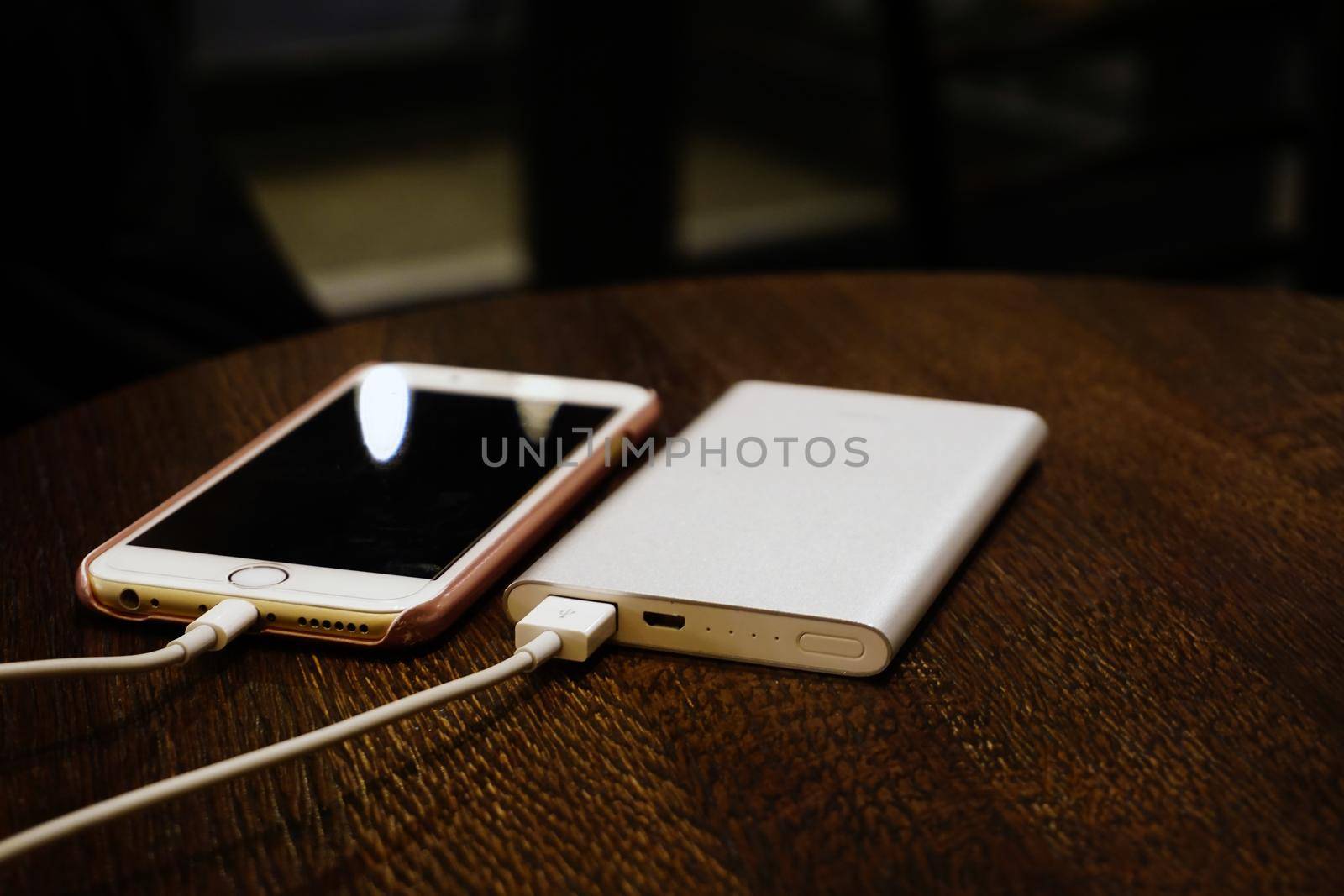 Powerbank charging smartphone on wooden background close up view