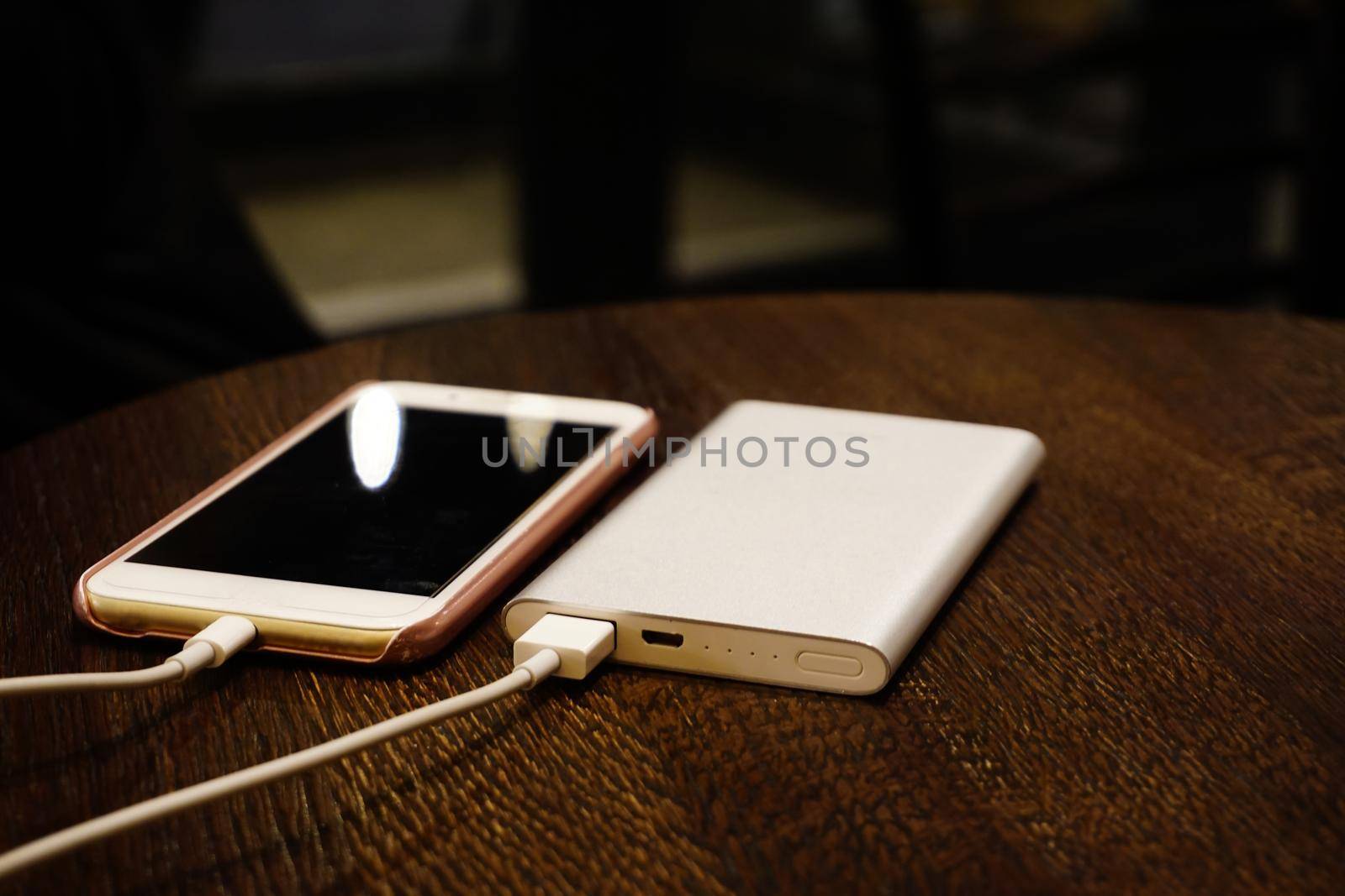 Powerbank charging smartphone close up view on wooden background